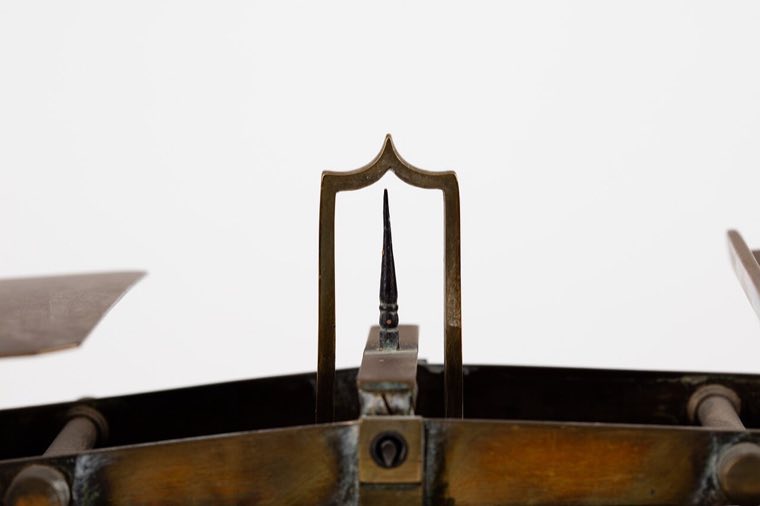 An antique brass balance scale sitting level, neither side tipped
